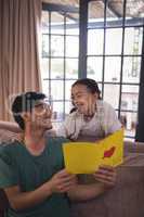 Father and daughter holding greeting card in living room