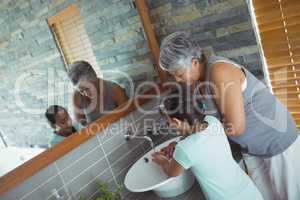 Grandmother and granddaughter washing hands in bathroom sink