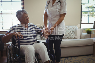 Female doctor interacting with senior woman on wheelchair