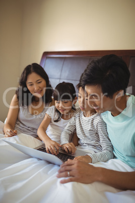 Family using laptop together in bedroom