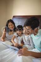 Family using laptop together in bedroom