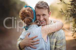 Smiling young man embracing woman at olive farm