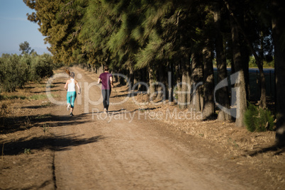 Rear view of young couple running on dirt road