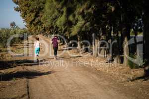 Rear view of young couple running on dirt road