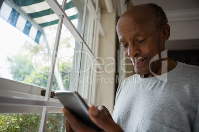 Senior man using mobile phone by window