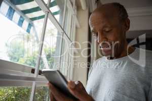 Senior man using mobile phone by window