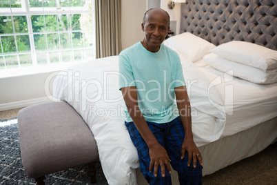Portrait of senior man sitting on bed at home