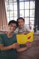 Father and daughter holding greeting card in living room