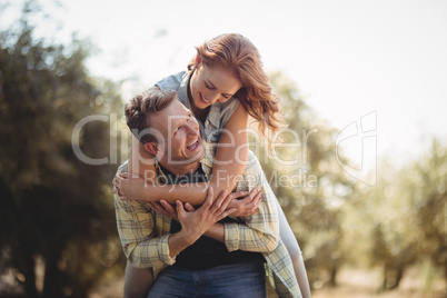 Smiling man piggybacking woman at olive farm