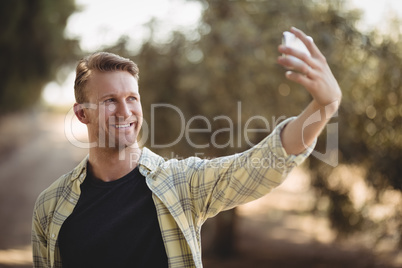 Smiling man taking selfie at olive farm