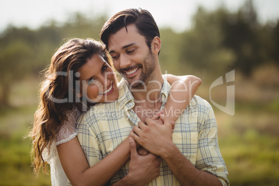 Young woman embracing man on sunny day at farm