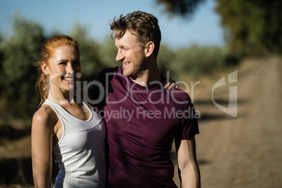 Young woman with man standing at farm on sunny day