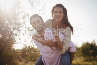 Handsome young man piggybacking woman at farm