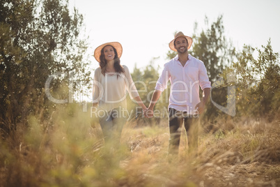Smiling young couple holding hands at farm