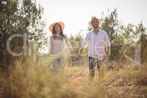 Smiling young couple holding hands at farm