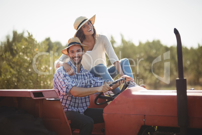Portrait of happy couple sitting together on tractor