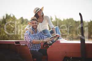 Portrait of happy couple sitting together on tractor