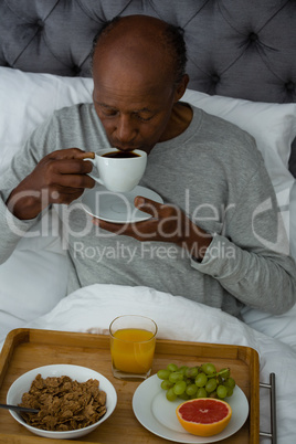 Senior man having breakfast while sitting on bed