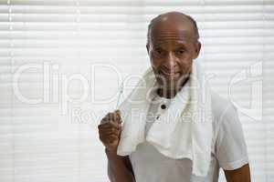 Portrait of senior man holding toothbrush against window