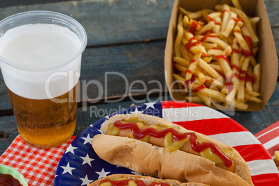 Hot dog served on plate with french fries and beer