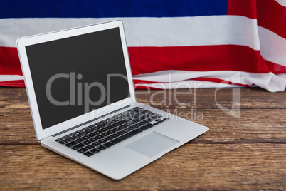 Laptop and American flag on wooden table
