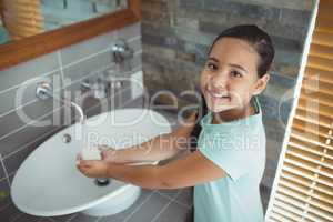 Girl washing hands in bathroom sink