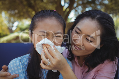 Mother helping daughter blow her nose