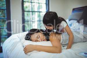 Mother and daughter relaxing on bed in bed room