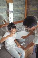 Son brushing his teeth with father in bathroom