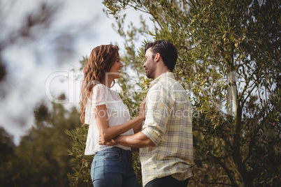 Loving young couple standing by trees at farm