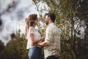 Loving young couple standing by trees at farm