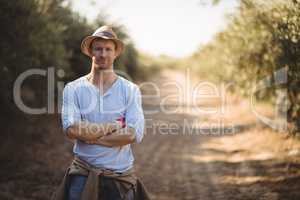 Confident young man standing on dirt road at farm