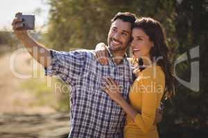 Smiling young couple taking selfie at olive farm