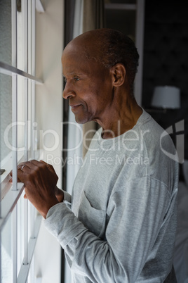 Side view of senior man looking out through window