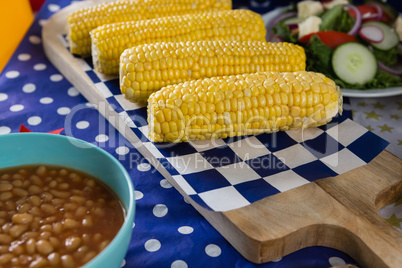 Baked beans and corn cob on wooden table with 4th july theme
