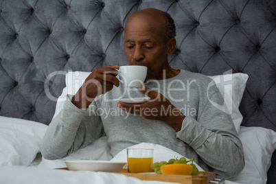 Senior man having breakfast on bed