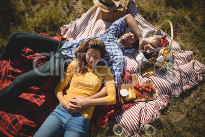 High angle view of young couple resting together on picnic blanket