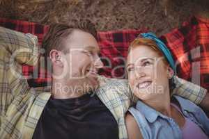 Smiling young couple lying on mat at farm