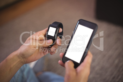 Man using smart watch and mobile phone in living room
