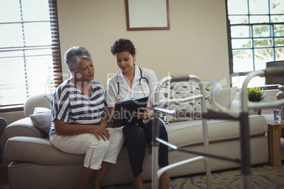 Female doctor interacting with senior woman in living room