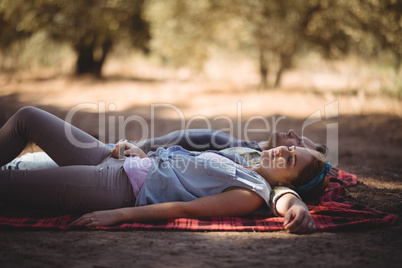 Young couple napping on mat at olive farm