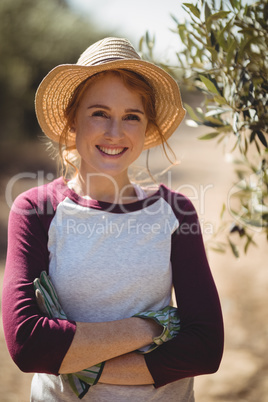 Smiling young woman with arms crossed standing at olive farm