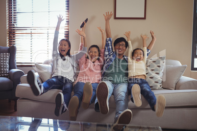 Smiling family watching television together in living room