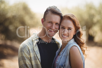 Portrait of happy young couple standing at olive farm