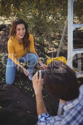 Boyfriend photographing smiling girlfriend at olive farm