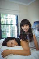 Mother and daughter relaxing on bed in bed room