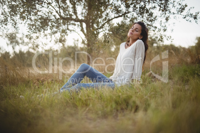 Young woman resting on grassy field at farm