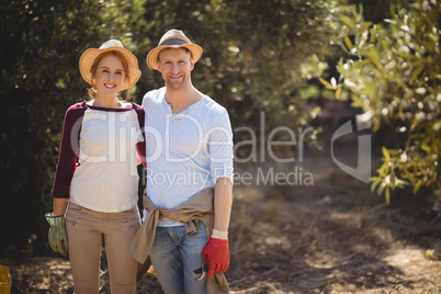 Happy couple standing at olive farm on sunny day