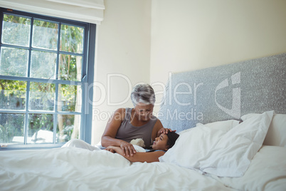 Grandmother comforting sick granddaughter in bed room