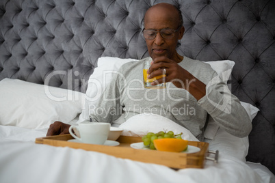 Senior man having breakfast on bed at home